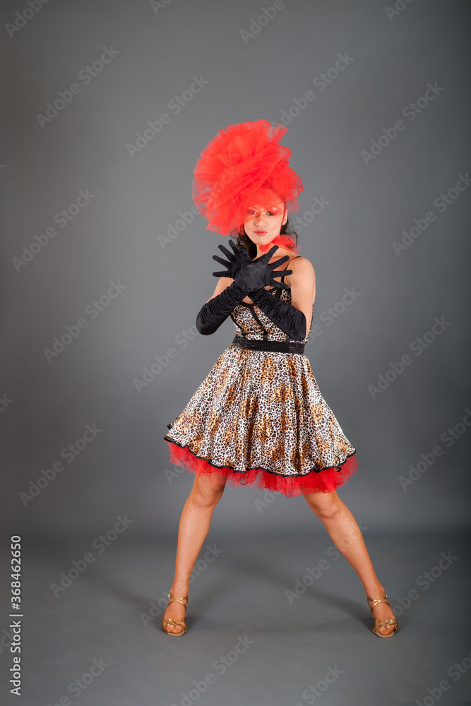 young brunette woman in leopard printed dress and red hat poses on hight heels young brunette woman in leopard printed dress and red hat poses on hight heels