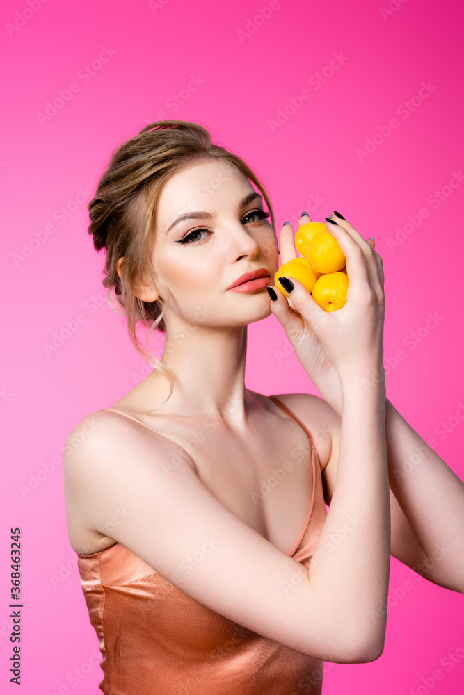 elegant beautiful blonde woman in silk dress holding ripe apricots isolated on pink elegant beautiful blonde woman in silk dress holding ripe apricots isolated on pink