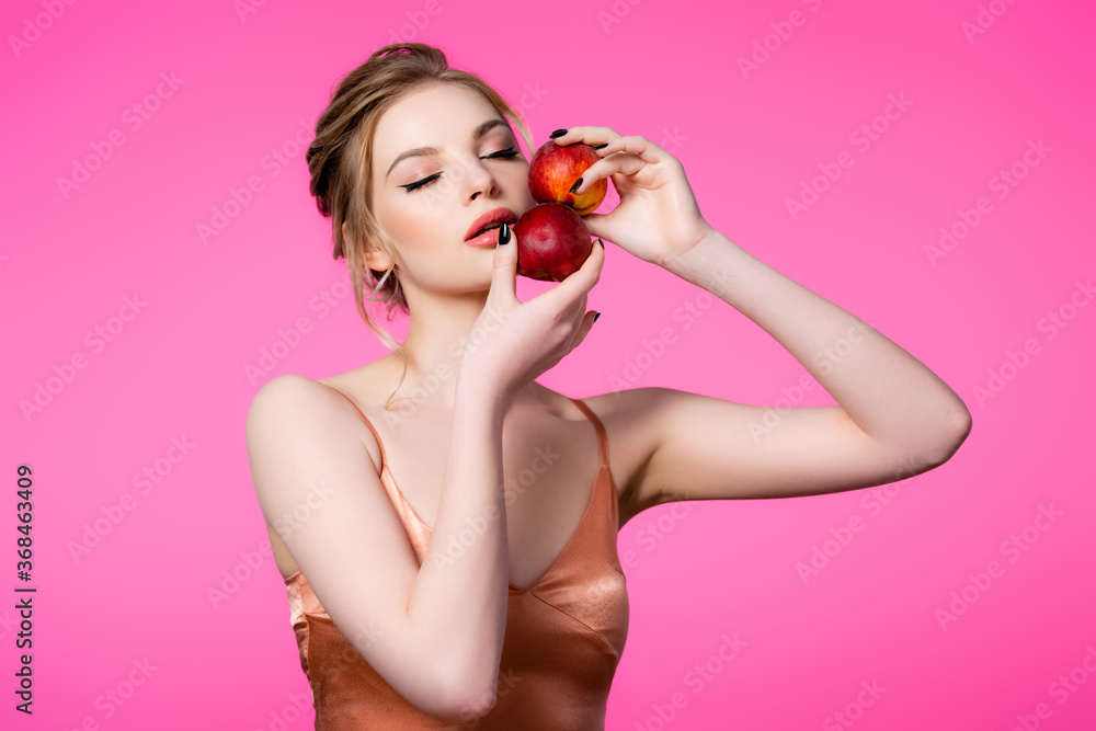 elegant beautiful blonde woman in silk dress with closed eyes holding peaches isolated on pink elegant beautiful blonde woman in silk dress with closed eyes holding peaches isolated on pink