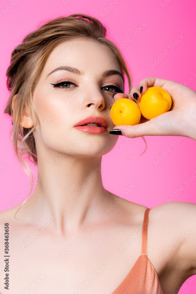 elegant beautiful blonde woman holding apricots isolated on pink elegant beautiful blonde woman holding apricots isolated on pink