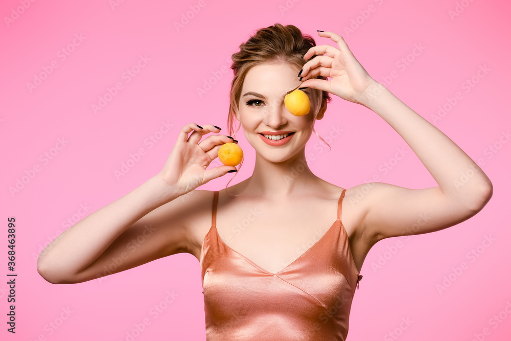 smiling elegant beautiful blonde woman in silk dress holding apricots isolated on pink smiling elegant beautiful blonde woman in silk dress holding apricots isolated on pink