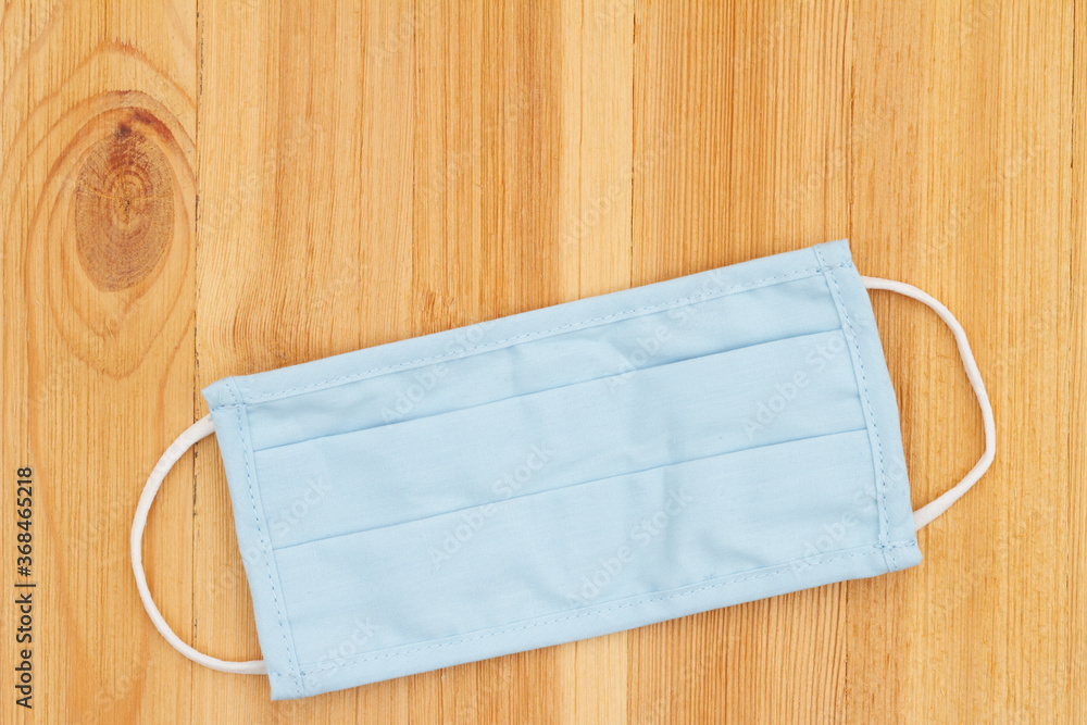 Blue cloth face mask on a wood desk Blue cloth face mask on a wood desk