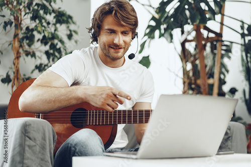 Young man watching guitar tutorial on his laptop