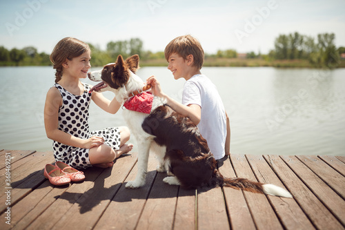 Brother and sister enjoy sunny day with their dog on the dock