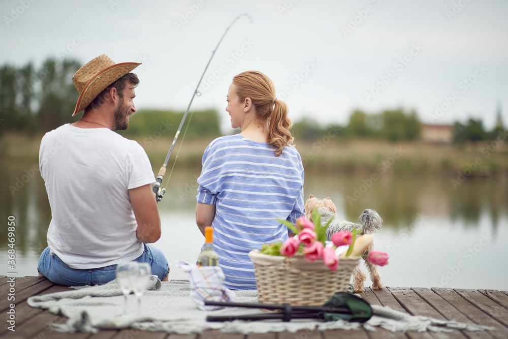 Happy spouses enjoy fishing and a picnic with their dog Happy spouses enjoy fishing and a picnic with their dog