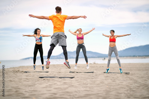 Fitness people jumping and fitness workout on the beach..