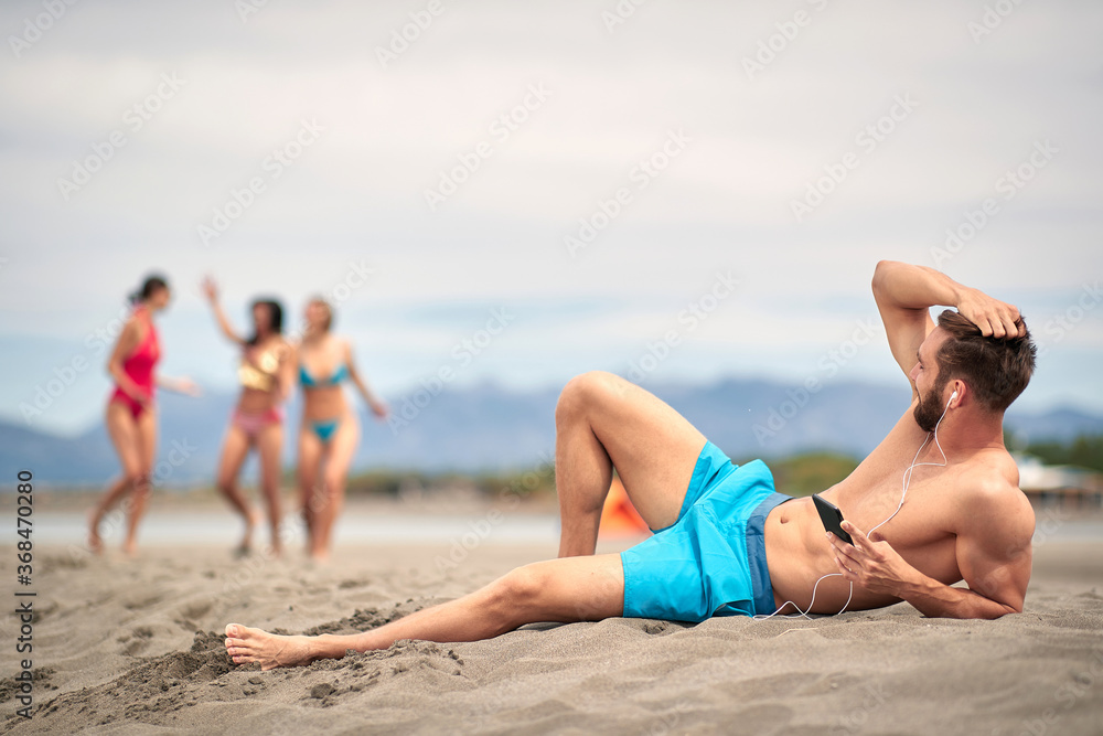 Young man relaxing at the beach at vacation and listens to music. Young man relaxing at the beach at vacation and listens to music.