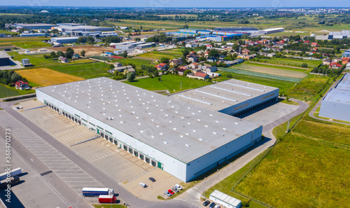 Aerial view of goods warehouse. Logistics center in industrial city zone from above. Aerial view of trucks loading at logistic center. View from drone. photo