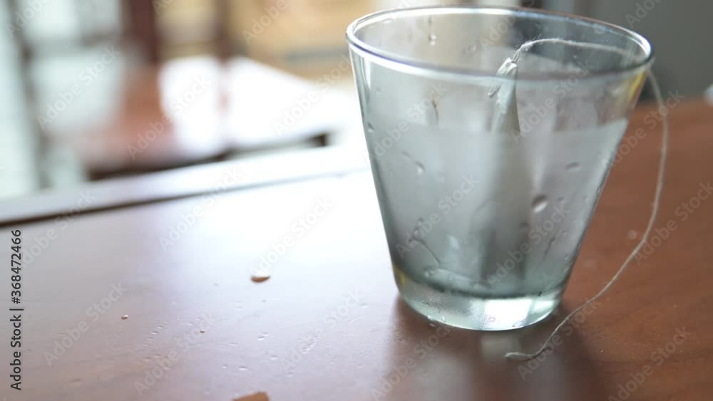 Close-up image of preparation of a cold herbal tea: the sachet containing the infusion is placed in the glass, then it is filled with cold water. The glass is covered with condensation. Close-up image of preparation of a cold herbal tea: the sachet containing the infusion is placed in the glass, then it is filled with cold water. The glass is covered with condensation.