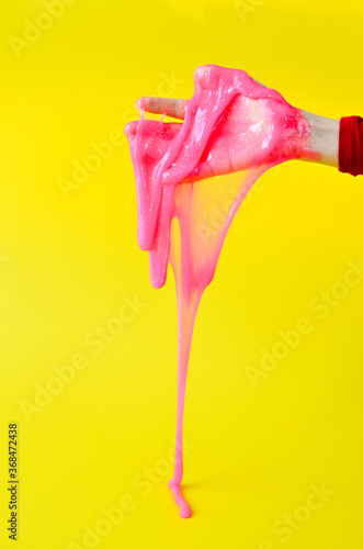 The toy for children mucus and liquid flowing on hand on a yellow background