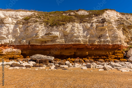 A close-up view of the stratified white, red and orange layers and recent rock falls on the cliffs of Old Hunstanton, Norfolk, UK photo