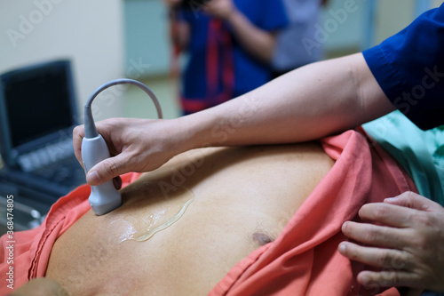 Physician making echocardiography for male patient heart by using ultrasound probe press on patient’s breast