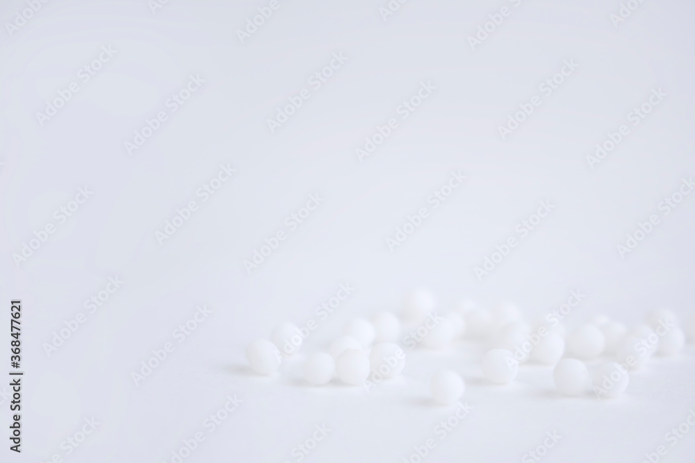 Homeopathic globules scattered on a white background. Alternative Homeopathy medicine herbs, health care and pills concept. copy space.