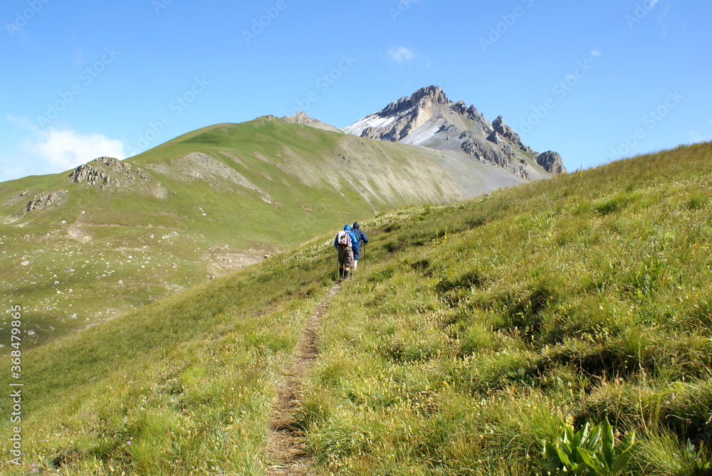 Two trekkers walking along a mountain path in Roburent, Piedmont (Italy)