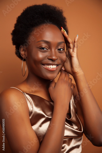 young pretty african girl with fashion makeup posing cheeful on brown background, lifestyle people concept