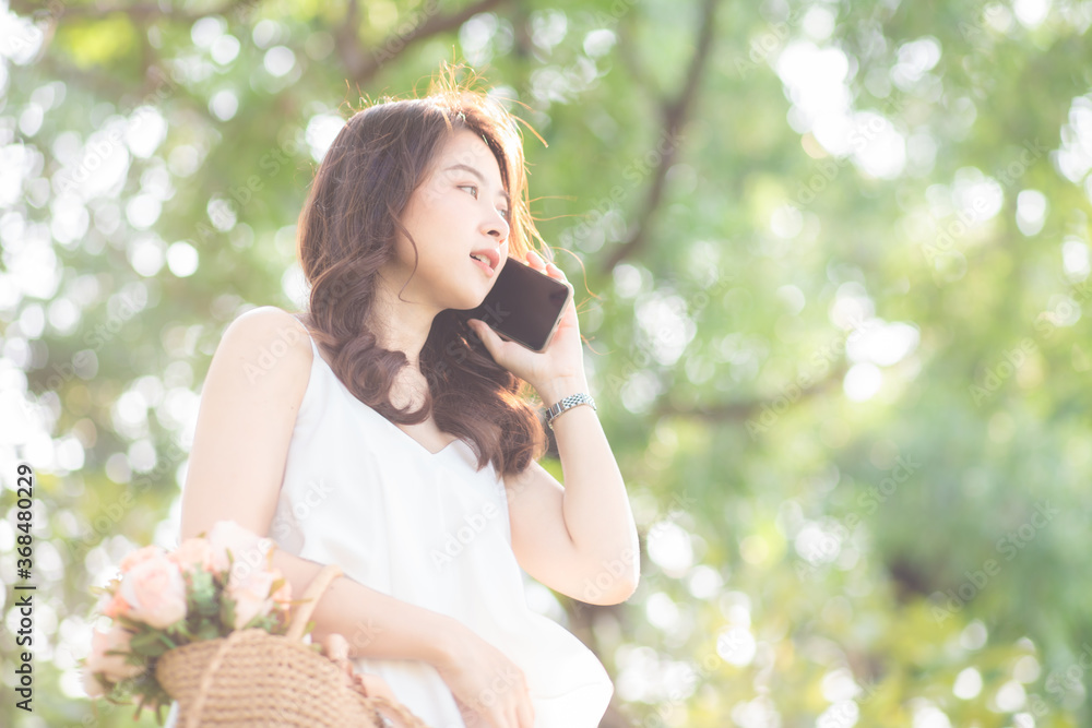 Cheerful young woman talking smartphone in city green park Cheerful young woman talking smartphone in city green park