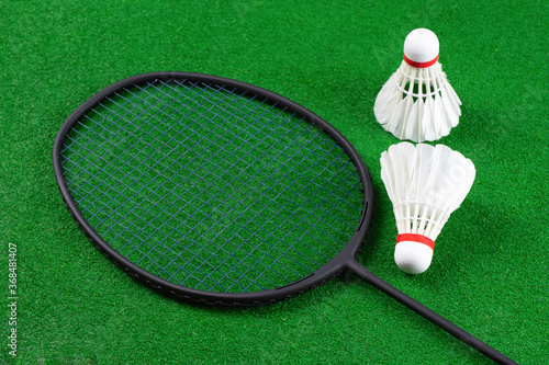Close-up of a pair of feathers badminton shuttlecock and racket placed on the badminton court.