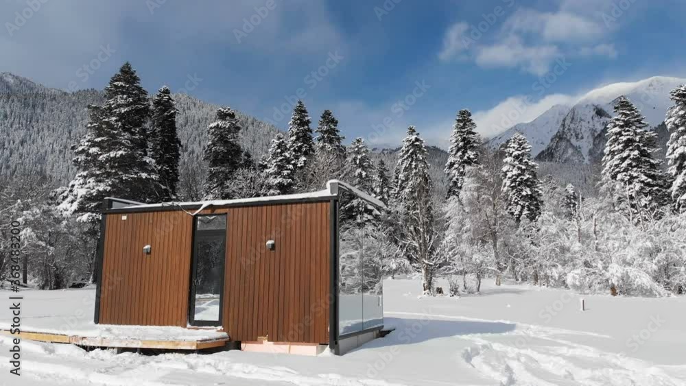 Aerial view of an innovative high-tech house with mirrored walls amid a winter forest in the mountains. The concept of eco tourism in the mountains. Modern architecture in nature reserves Aerial view of an innovative high-tech house with mirrored walls amid a winter forest in the mountains. The concept of eco tourism in the mountains. Modern architecture in nature reserves