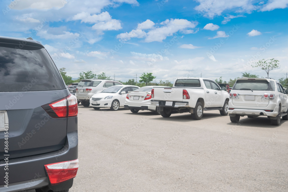 Car parked in large asphalt parking lot and back car close up with cloudy sky background. Outdoor parking lot  travel transportation