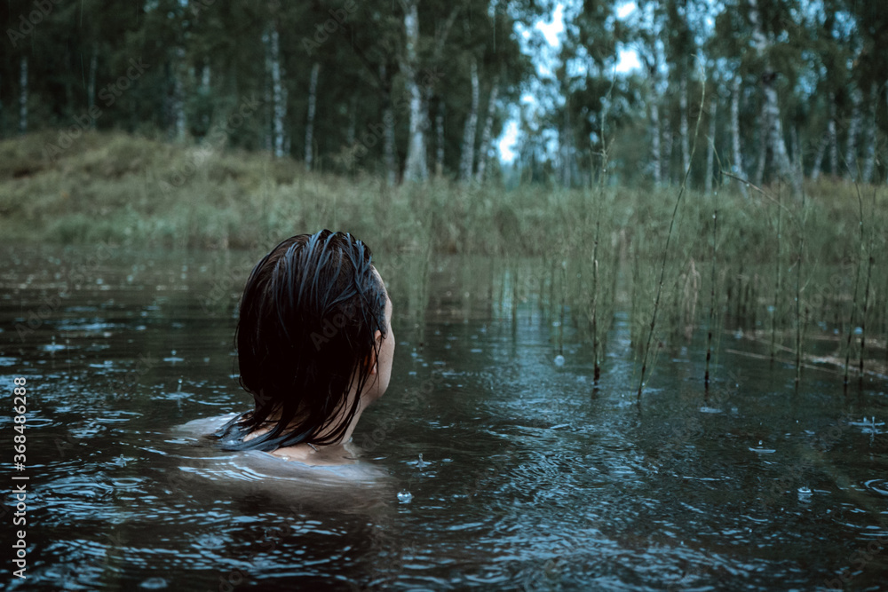 Fototapeta premium Beautiful young woman swimming in in the forest lake