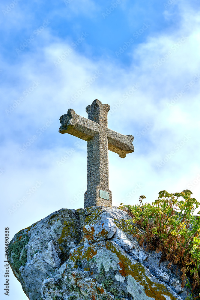 stone christian cross on top of a mountain with clouds