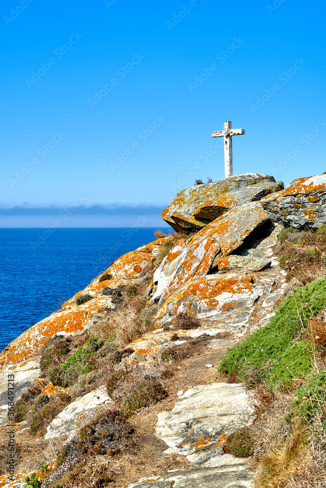 white christian cross on top of a mountain with sea in the background