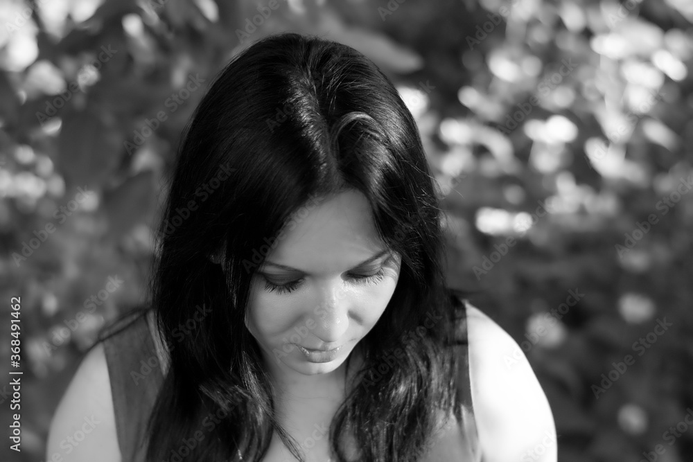 Black and white portrait of a woman looking at something. Brunette looks down