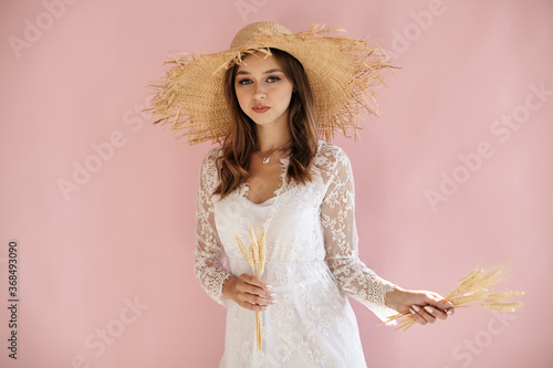Girl on a pink background in a straw hat