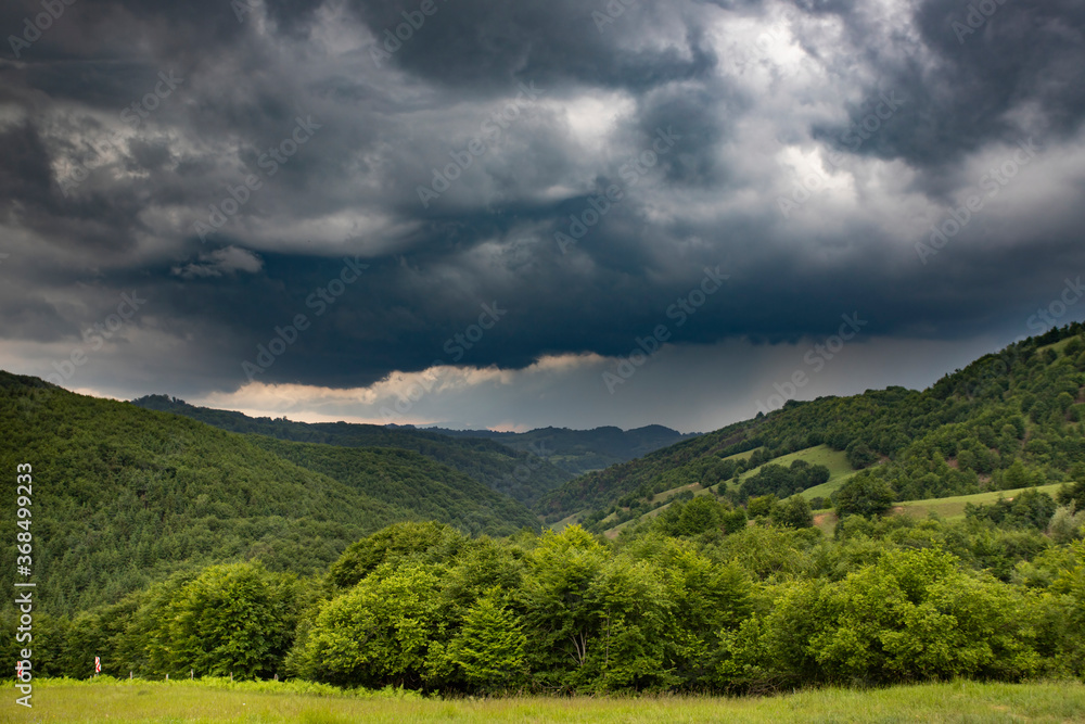 Storm clouds above meadow with green grass