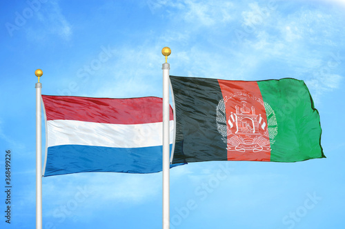 Netherlands and Afghanistan two flags on flagpoles and blue sky