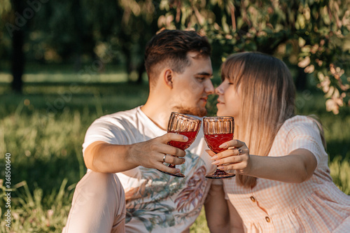 young happy couple in the park holding glasses with juice in their hands