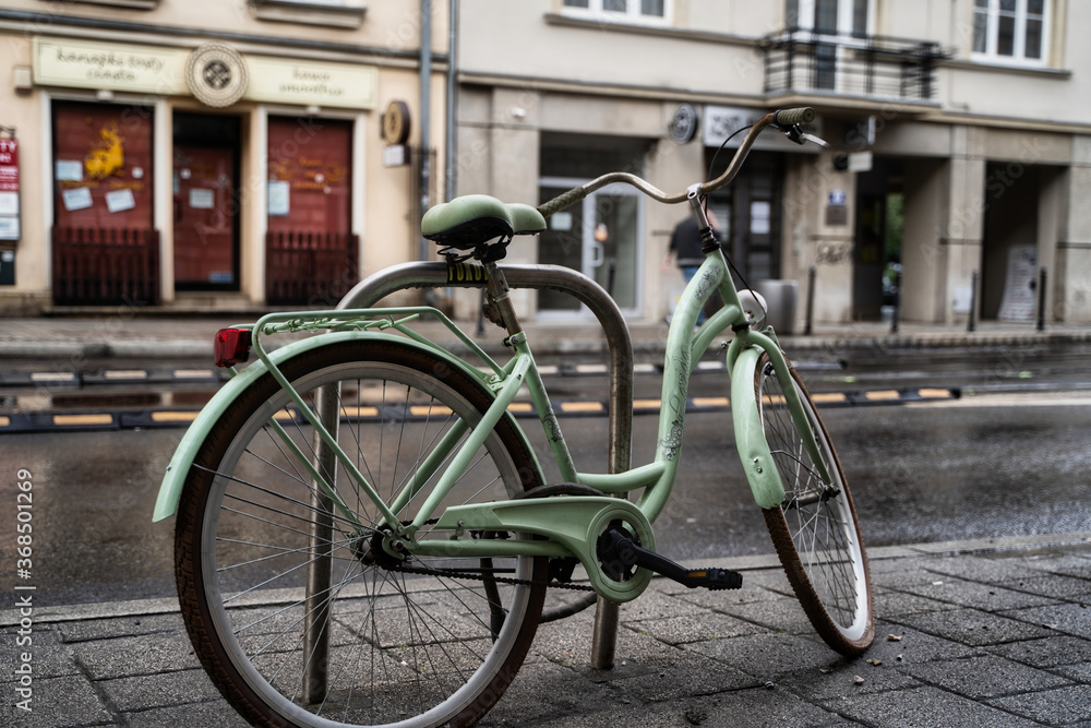 Krakow, Poland - July 18, 2020: A closeup of a white bicycle parked next to busy street in krakow in rainy weather