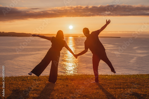 silhouette of a couple walking on the beach at sunset