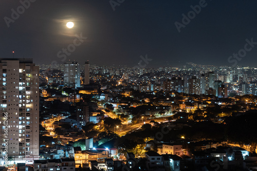 Foto noturna da cidade incluindo a Lua. 