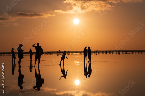 Beautiful sunset on the lake, the sun reflecting in the water, silhouettes of people reflected in the water