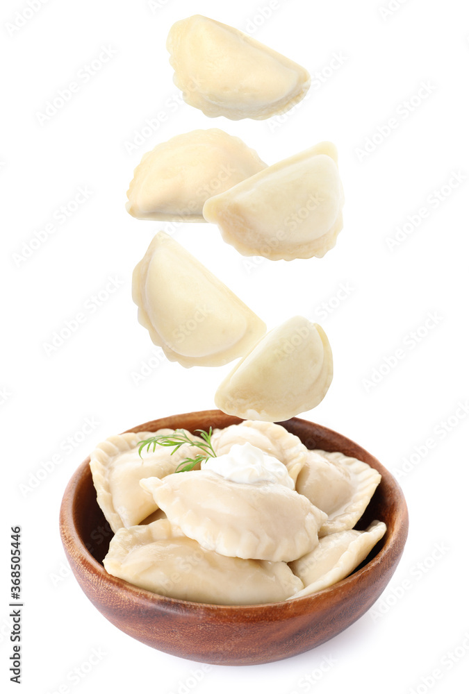 Many tasty dumplings falling into wooden bowl on white background Many tasty dumplings falling into wooden bowl on white background