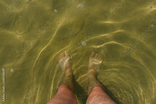 Male feet in the water of the lake © Roman
