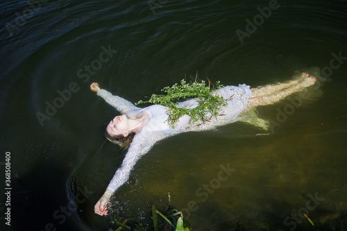 Young white woman with long blondy hair in a river in a forest in summer