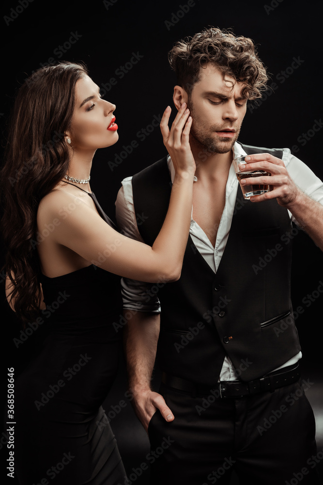 Sexy woman touching boyfriend with glass of whiskey on black Sexy woman touching boyfriend with glass of whiskey on black