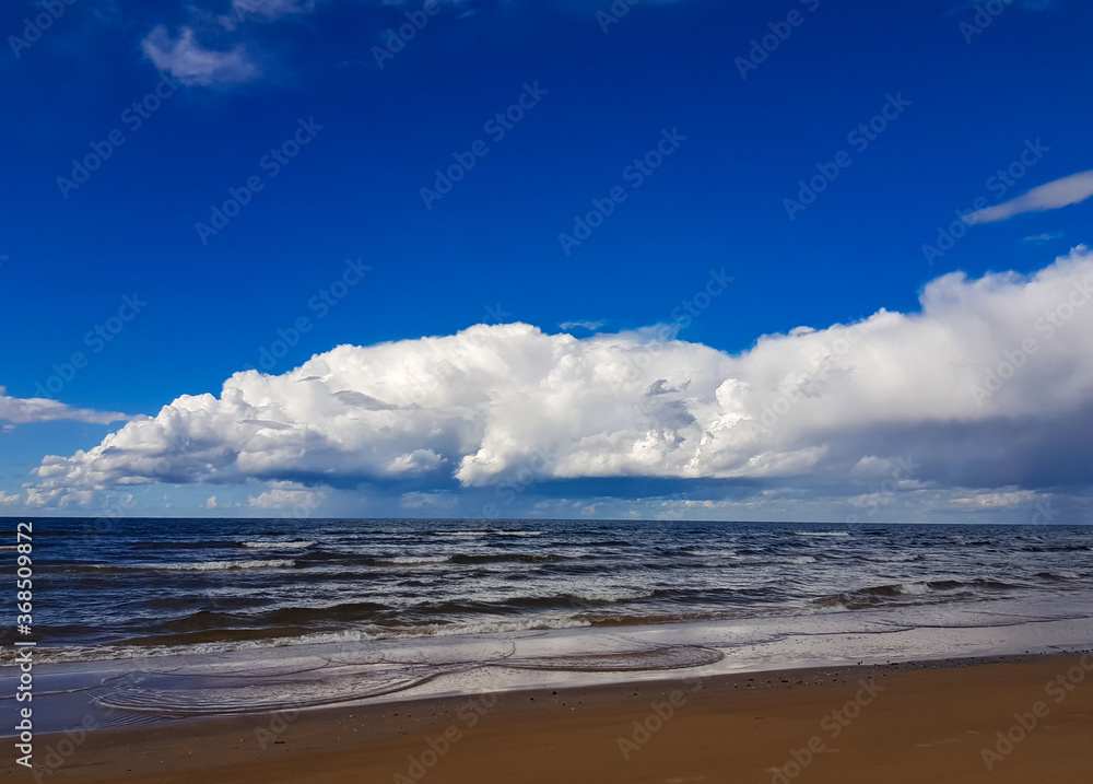 Cumulus clouds over wild coast of the Baltic Sea in Latvia