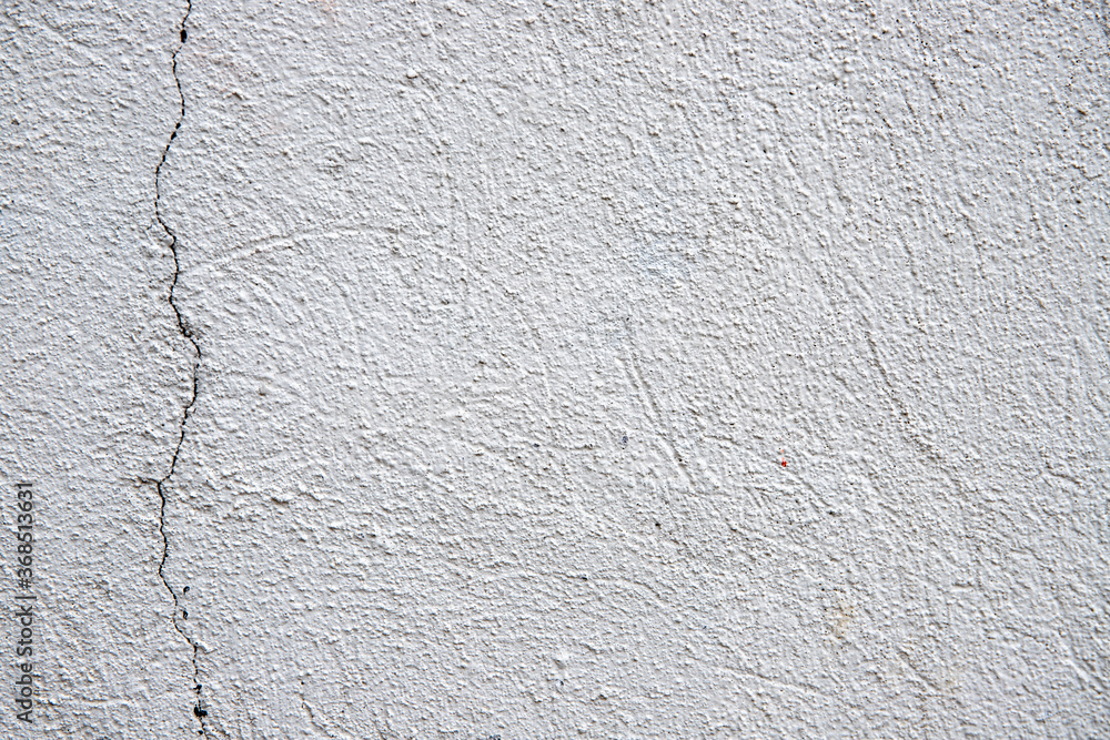 White plaster painted wall with grain and cracks. Cracked wall closeup photo. Architecture detail background. Empty concrete wall. Grungy surface of painted cement. Abstract grainy texture White plaster painted wall with grain and cracks. Cracked wall closeup photo. Architecture detail background. Empty concrete wall. Grungy surface of painted cement. Abstract grainy texture