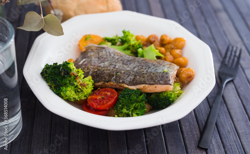 appetizing cooked trout, chickpeas, broccoli in white vintage bowl