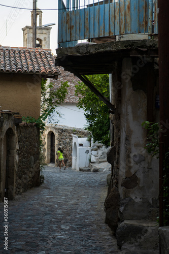 Fototapeta Naklejka Na Ścianę i Meble -  Picturesque narrow streets of old Kakopetria, Troodos mountains, Cyprus with a girl walking in the distance