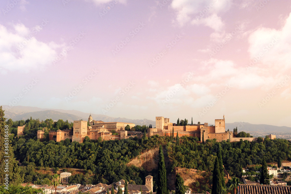colorful landscape of Granada city at sunset, with the Alhambra in the background, mountains, trees and the sky with clouds for a nice postcard or wallpaper