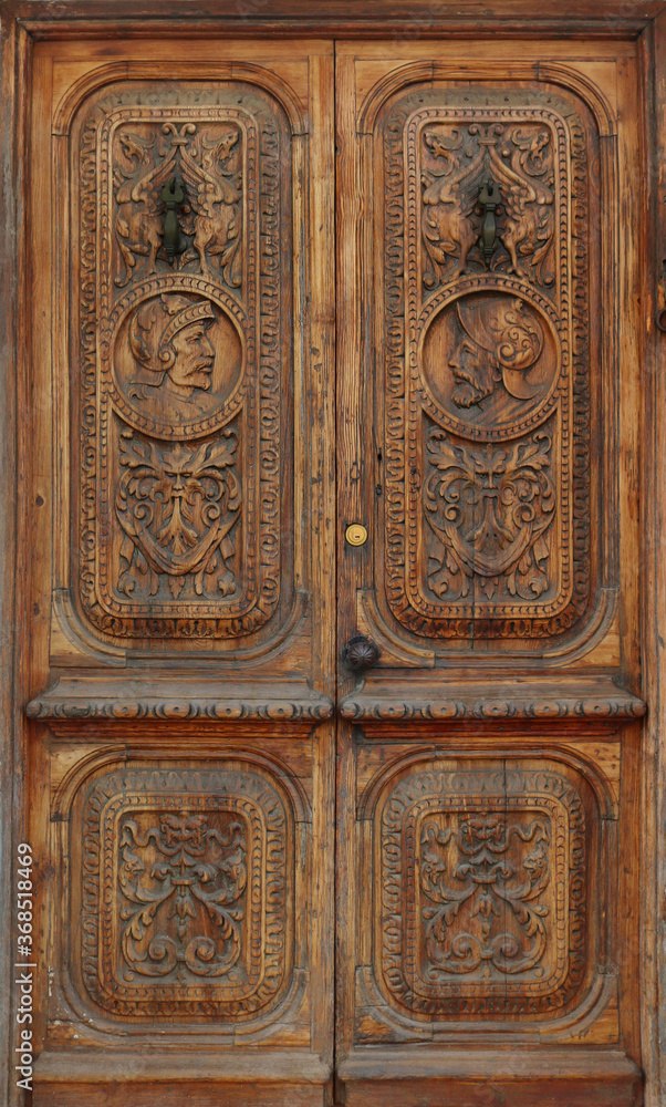 ancient and worn wooden gate with engraved ornaments in the wood