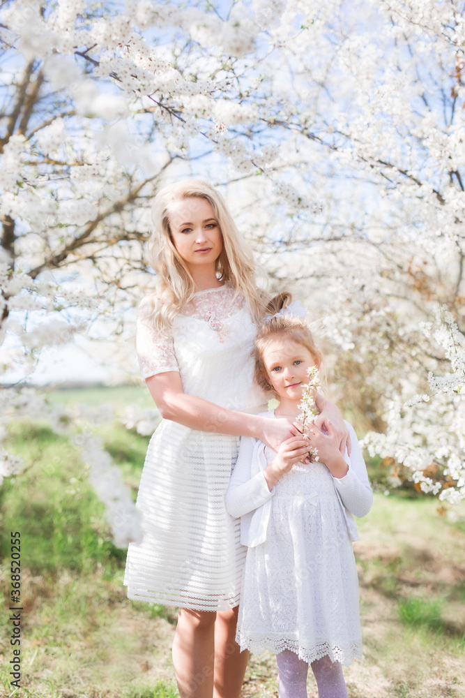 Young and beautiful mother with baby girl toddler in white dress. Family in park spend time together, tender, love, hugs, play. Stylish summer clothing. Young and beautiful mother with baby girl toddler in white dress. Family in park spend time together, tender, love, hugs, play. Stylish summer clothing.