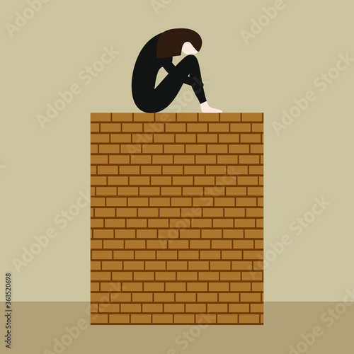 Girl sitting on a brick wall with her head bowed to her knees