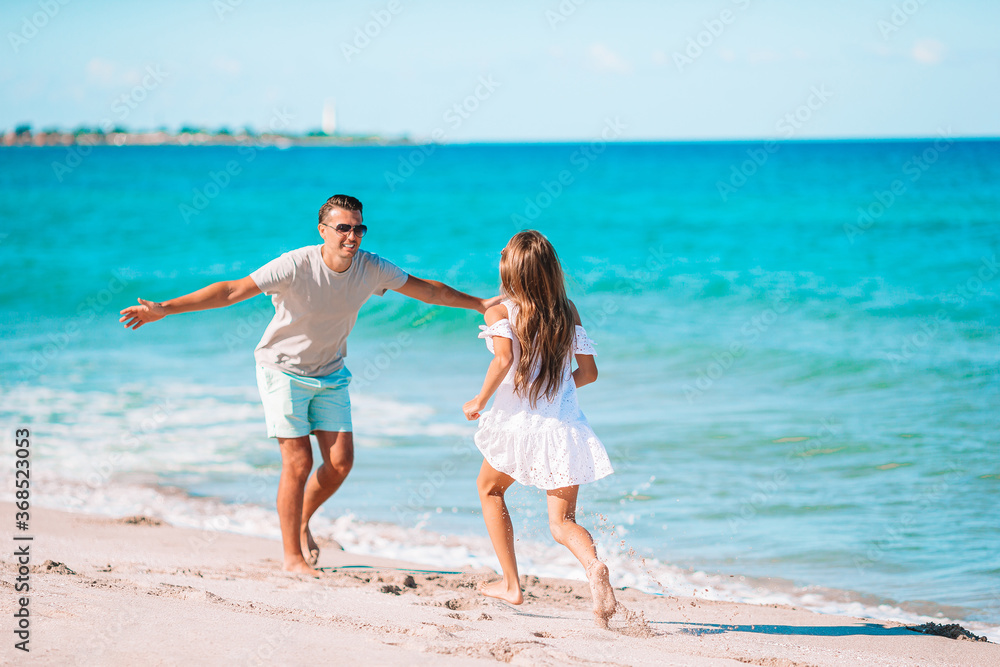 Naklejka premium Little girl and happy dad having fun during beach vacation