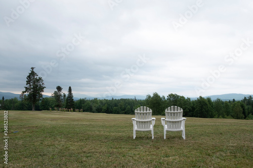 Two lawn chairs with no people positioned to overlook countryside.