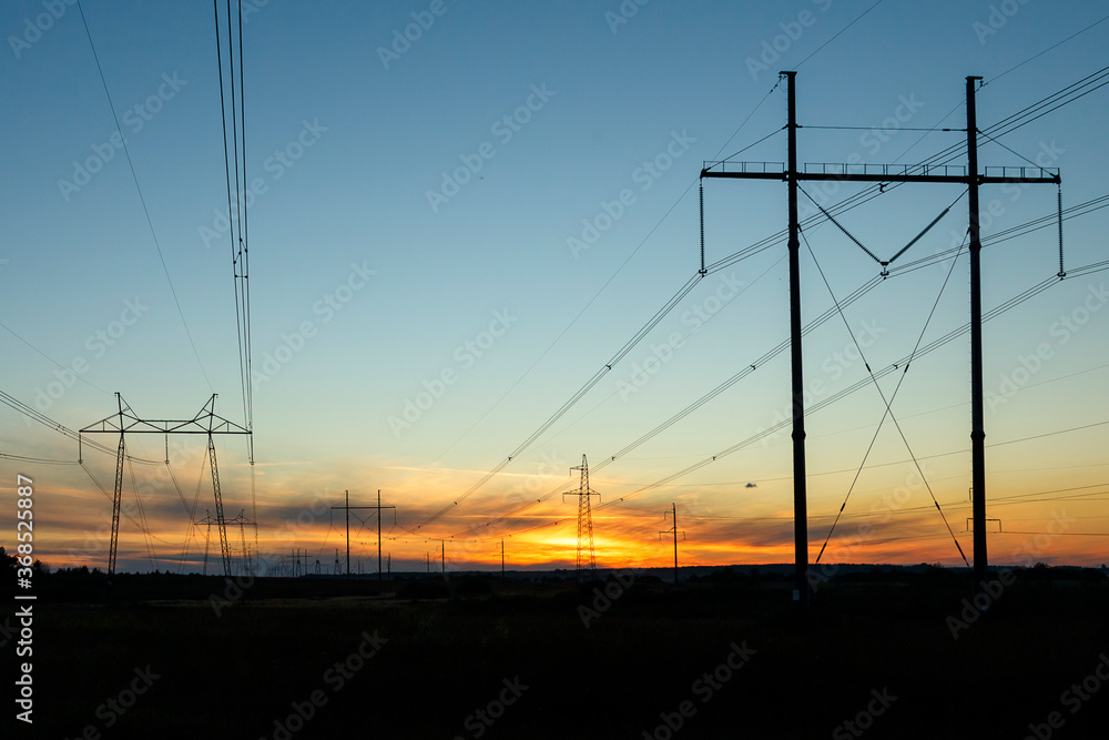 High-voltage power lines at sunset by the road. Horizontal